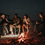 A group sitting around the campfire at night.