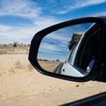 The side mirror in a 4x4 rental car on a road in Botswana.