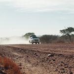 A 4x4 rental car driving on a murram road