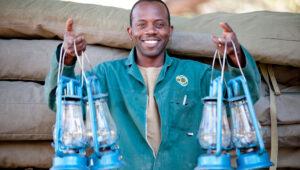 A member of the camping crew holds up several lanterns.