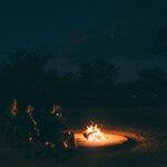 A group of travellers sitting around a campfire on their guided self-drive safari in Zambia.