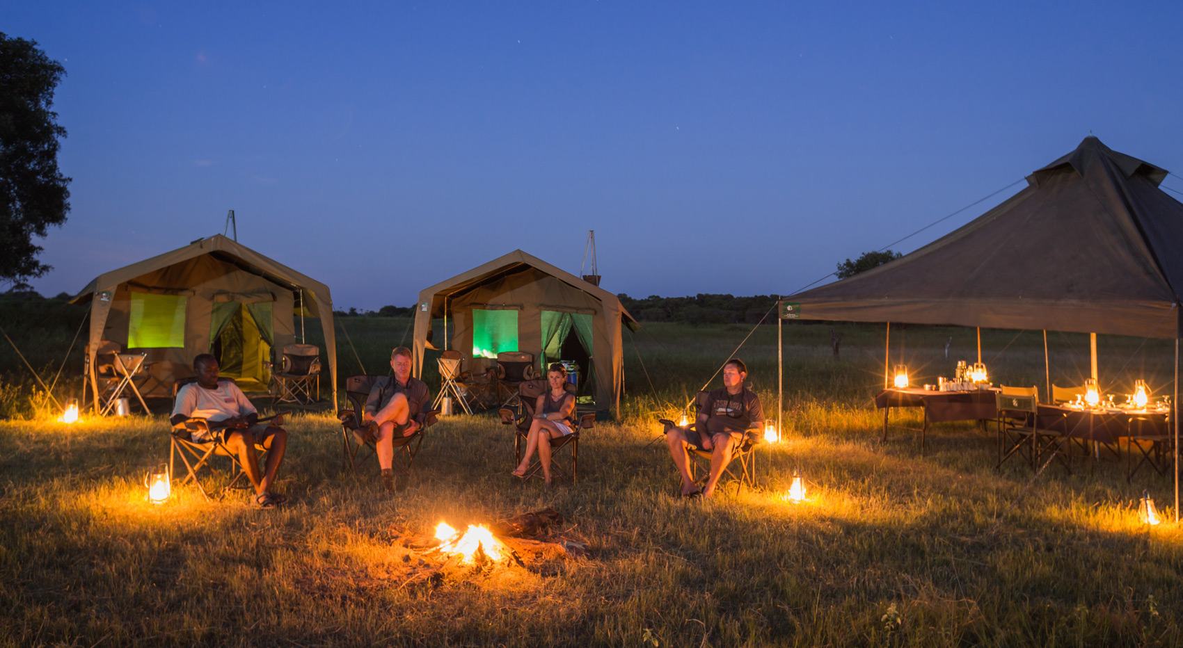 A photo of mobile tents with guests around a camp fire. A photo of mobile tents with guests around a camp fire.