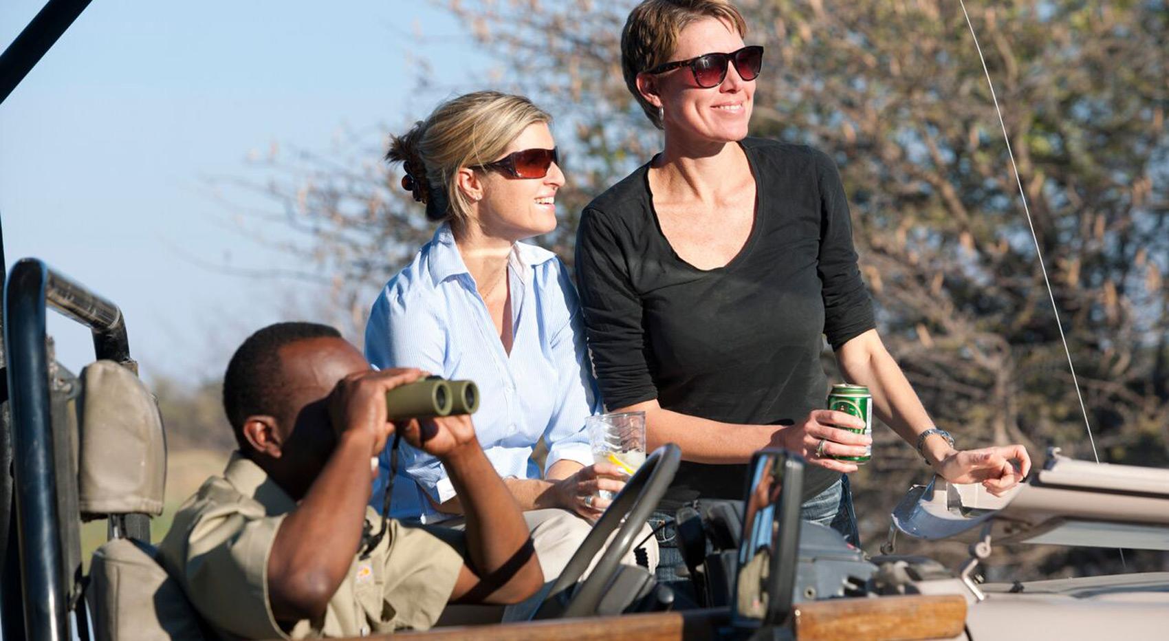 Guests and guide in an open game viewer used to travel in during Okavango Delta camping.