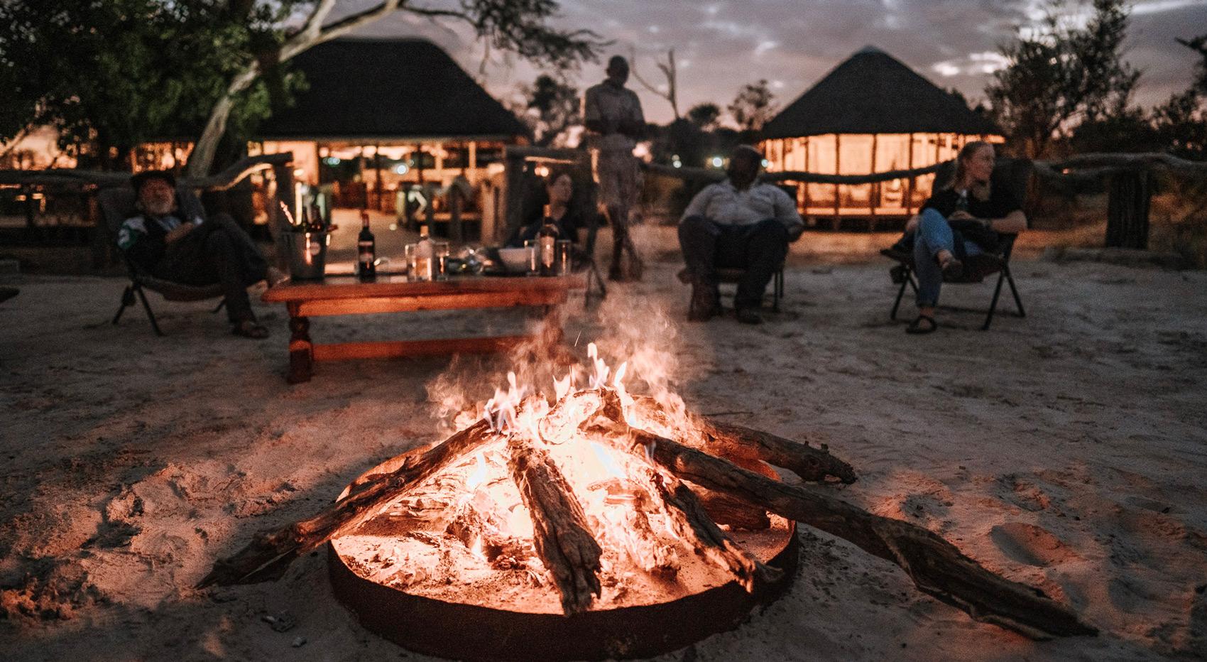 Gäste sitzen am Lagerfeuer in Botswana, ein beliebtes Erlebnis auf einer Botswana-Safari für Wiederkehrer. Gäste sitzen am Lagerfeuer in Botswana, ein beliebtes Erlebnis auf einer Botswana-Safari für Wiederkehrer.