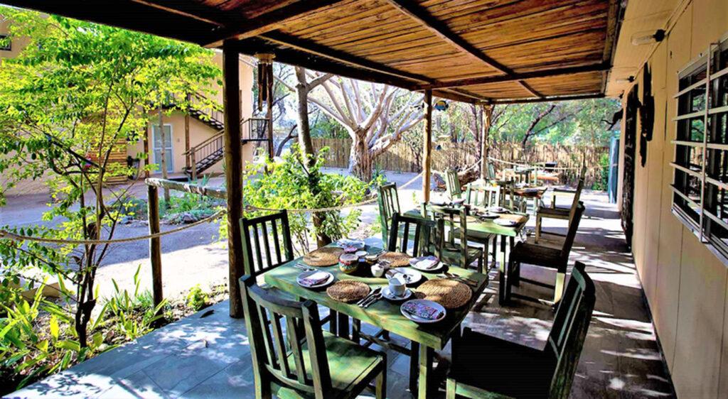 The breakfast verandah with set tables at Maun Waterfront Guesthouse.